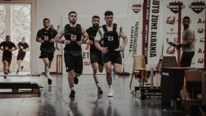Group of men running in an indoor fitness competition, showcasing athleticism and determination.